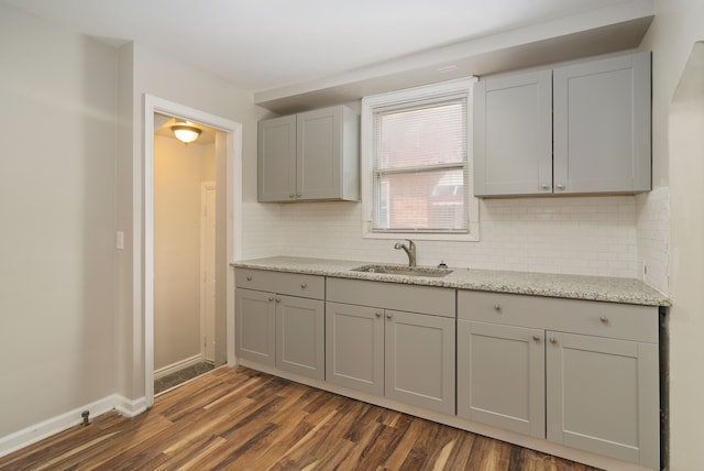 kitchen featuring tasteful backsplash, gray cabinetry, sink, and dark wood-type flooring