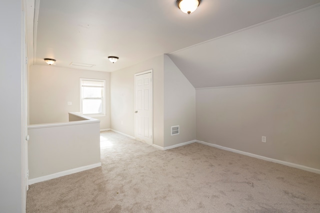 additional living space featuring light carpet and vaulted ceiling