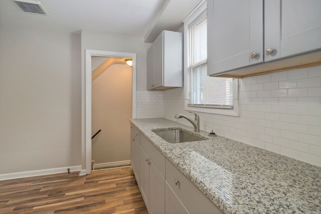 kitchen with light stone counters, sink, dark wood-type flooring, and plenty of natural light