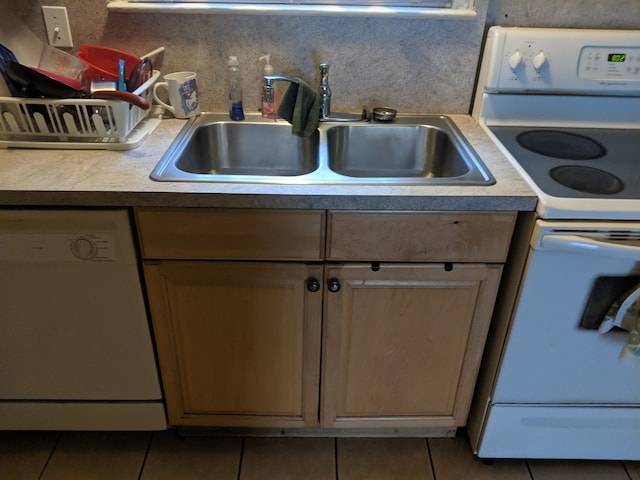 kitchen featuring tile patterned flooring, white appliances, and sink