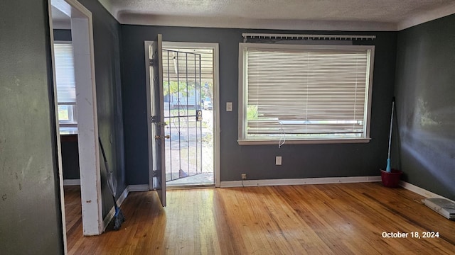 doorway to outside with a textured ceiling and light hardwood / wood-style flooring