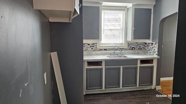 kitchen with decorative backsplash, dark hardwood / wood-style flooring, gray cabinetry, and sink