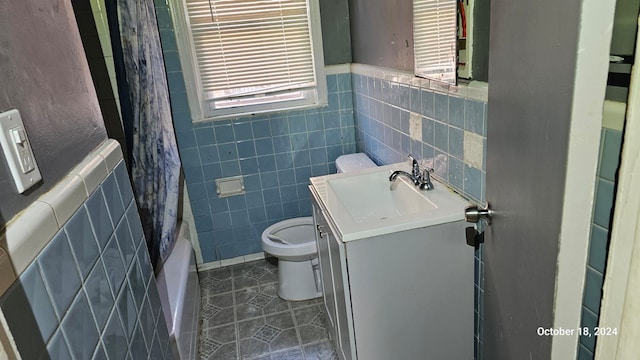 full bathroom featuring tile patterned floors, vanity, toilet, and tile walls