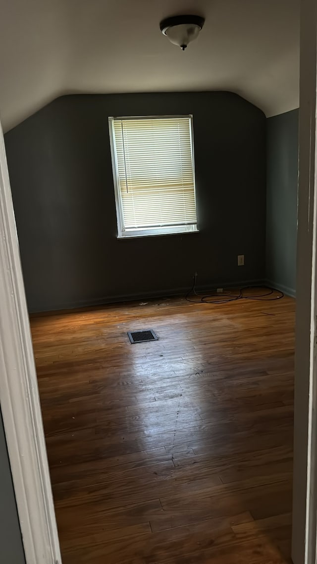 empty room featuring vaulted ceiling and dark wood-type flooring