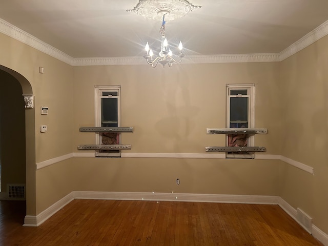 spare room featuring dark hardwood / wood-style flooring, an inviting chandelier, and crown molding