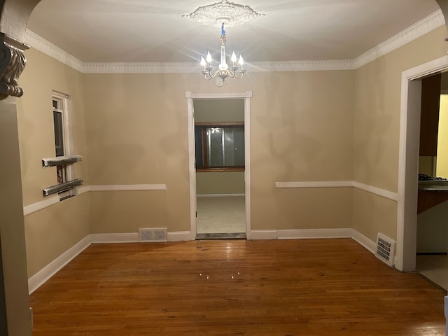 unfurnished dining area featuring hardwood / wood-style flooring, a notable chandelier, and ornamental molding