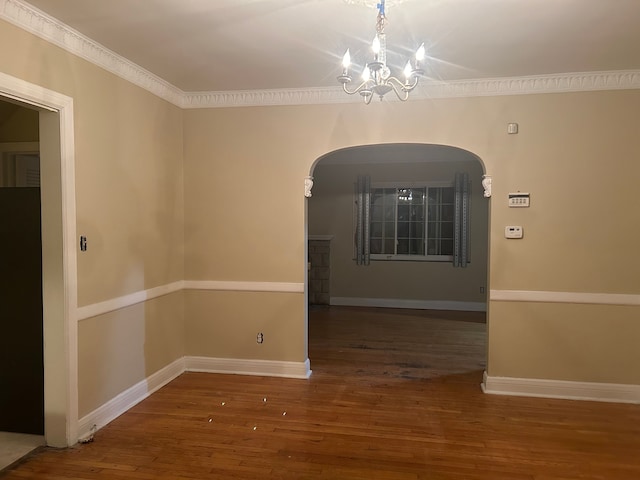 unfurnished room featuring an inviting chandelier, dark wood-type flooring, and ornamental molding