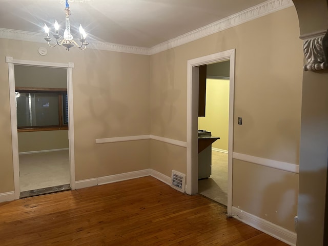 unfurnished room with crown molding, an inviting chandelier, and hardwood / wood-style flooring