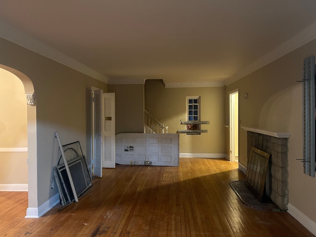 unfurnished living room featuring a stone fireplace, crown molding, and hardwood / wood-style flooring