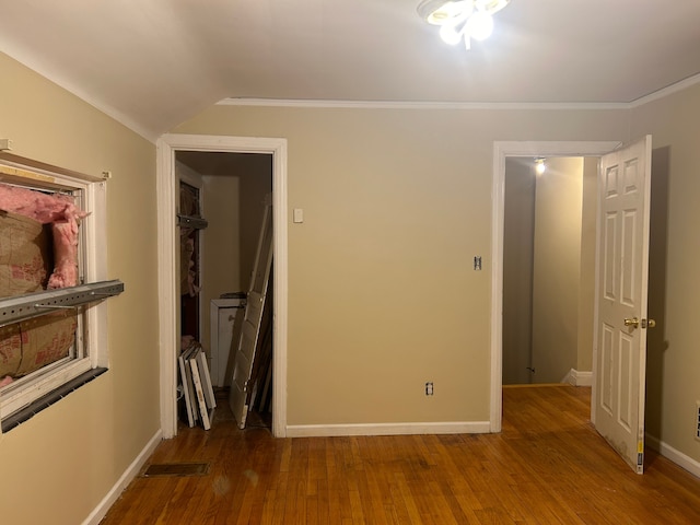 unfurnished bedroom with wood-type flooring, crown molding, and a closet