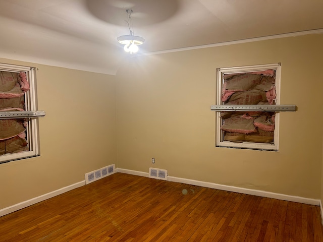 empty room with hardwood / wood-style flooring and ornamental molding