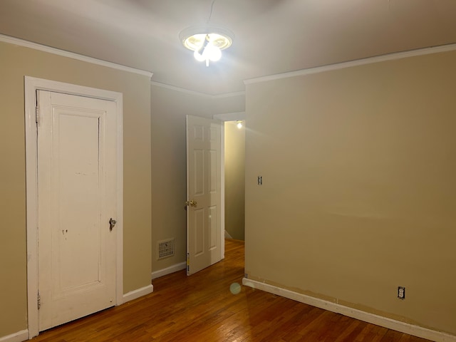 unfurnished bedroom featuring hardwood / wood-style flooring and crown molding