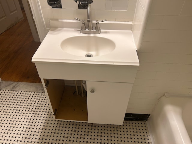 bathroom featuring hardwood / wood-style flooring, vanity, a bath, and tile walls