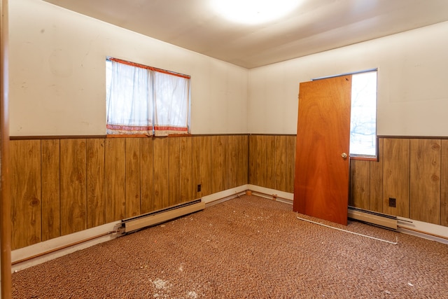 unfurnished room featuring wooden walls and a baseboard radiator