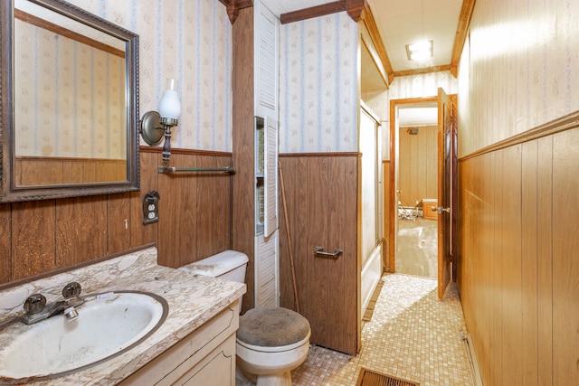 bathroom featuring vanity, wood walls, tile patterned floors, toilet, and ornamental molding