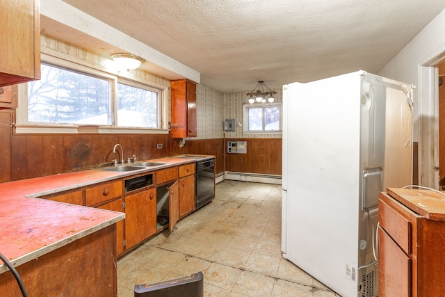 kitchen featuring wooden walls, sink, a baseboard radiator, and black dishwasher