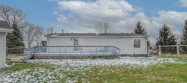 snow covered back of property featuring a wooden deck and a yard