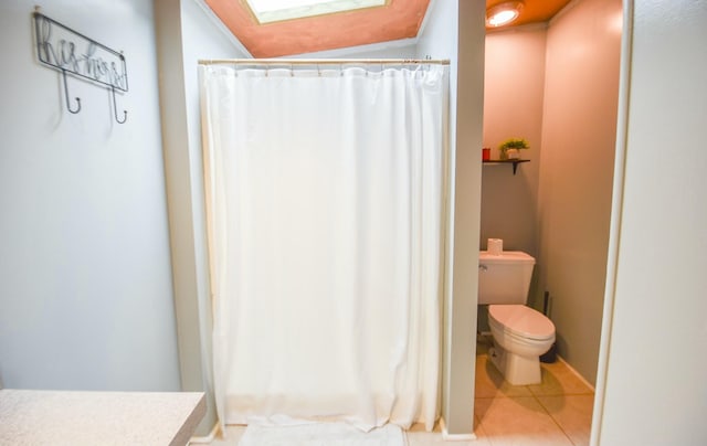 bathroom with tile patterned flooring, vanity, a skylight, and toilet