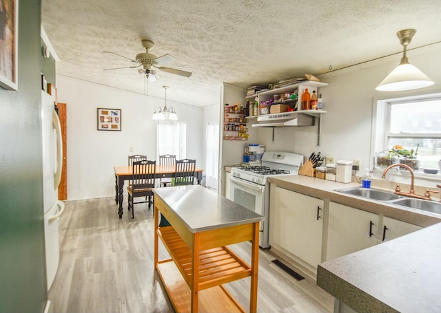 kitchen featuring white appliances, sink, decorative light fixtures, light hardwood / wood-style floors, and extractor fan