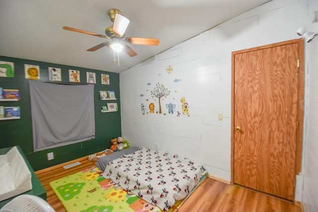 bedroom with ceiling fan, lofted ceiling, and light wood-type flooring