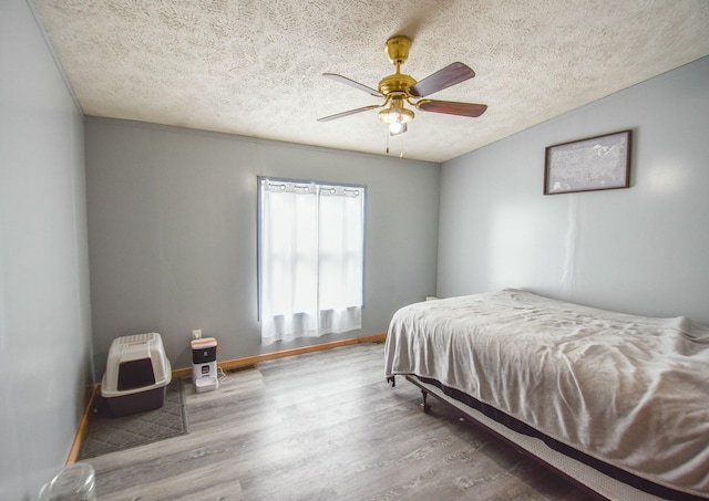 bedroom featuring hardwood / wood-style flooring, ceiling fan, and a textured ceiling