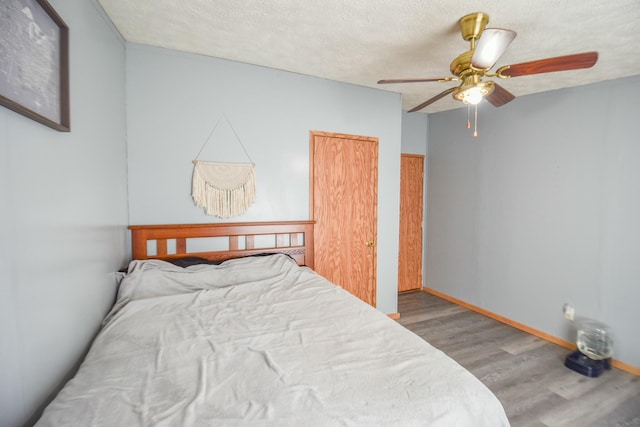 bedroom with hardwood / wood-style flooring, ceiling fan, and a textured ceiling