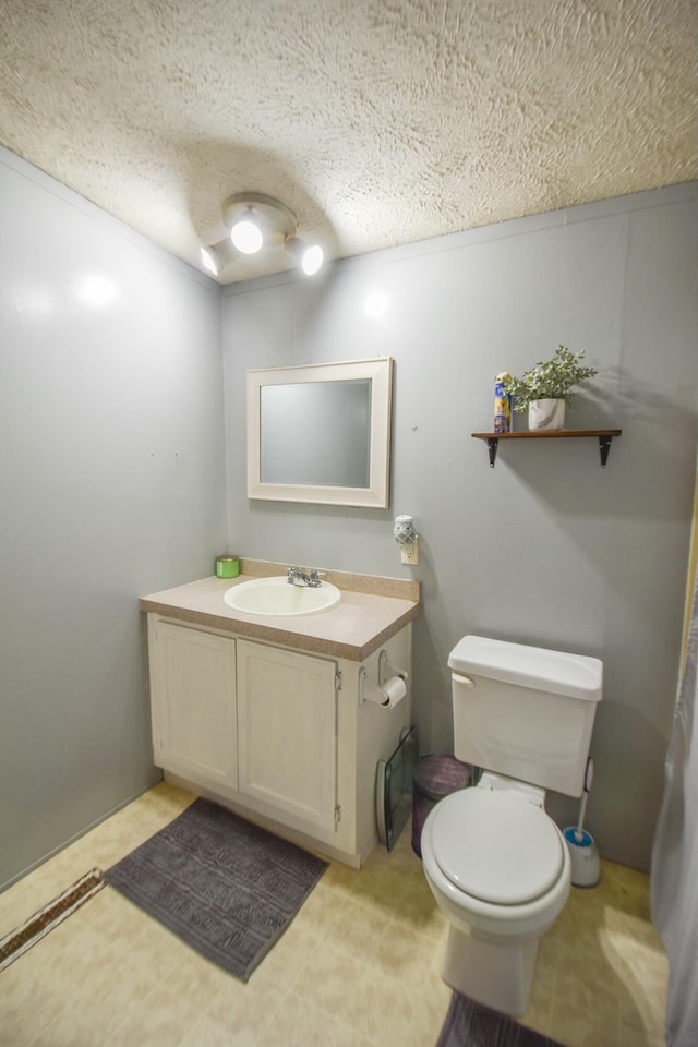 bathroom featuring vanity, a textured ceiling, and toilet