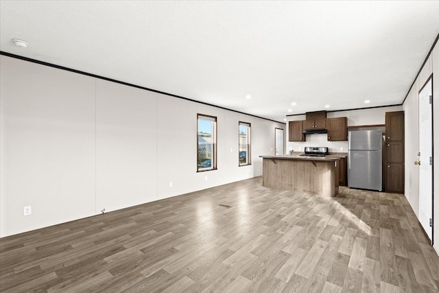 kitchen featuring stainless steel appliances, a kitchen breakfast bar, light hardwood / wood-style flooring, crown molding, and a kitchen island