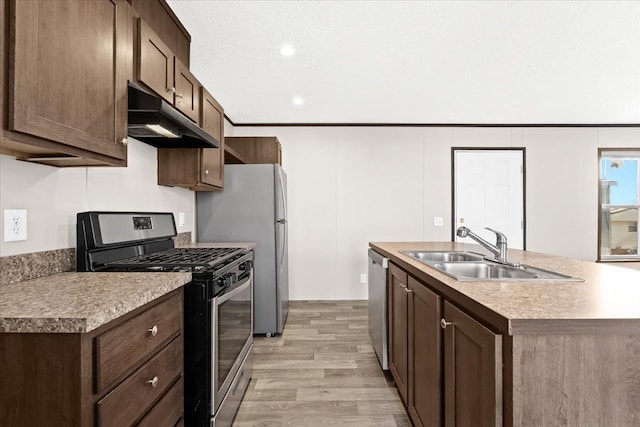 kitchen with a kitchen island with sink, sink, light hardwood / wood-style floors, dark brown cabinetry, and stainless steel appliances