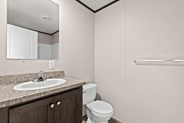 bathroom with crown molding, vanity, a textured ceiling, and toilet