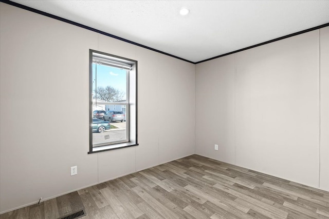 empty room featuring ornamental molding and light wood-type flooring