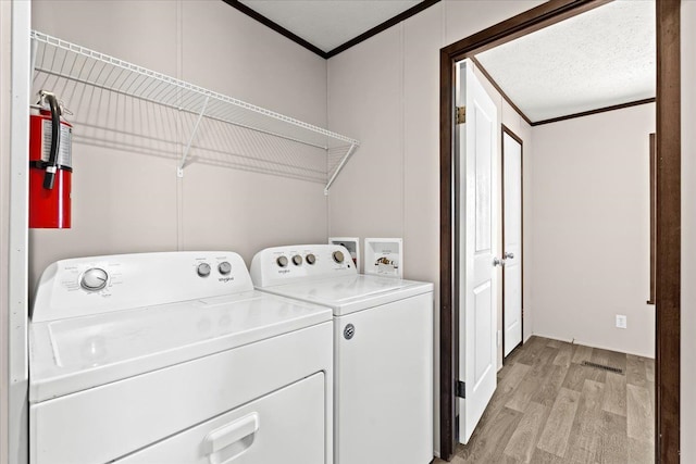 laundry area with light hardwood / wood-style floors, ornamental molding, and washing machine and clothes dryer