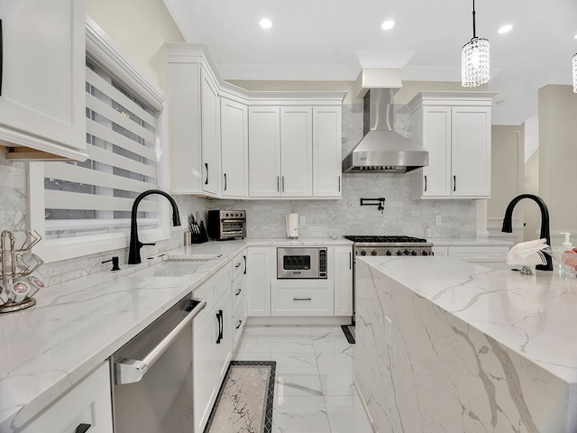 kitchen featuring wall chimney range hood, sink, light stone countertops, appliances with stainless steel finishes, and white cabinetry