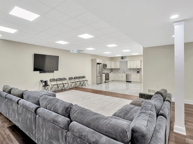 living room featuring a drop ceiling and light hardwood / wood-style floors