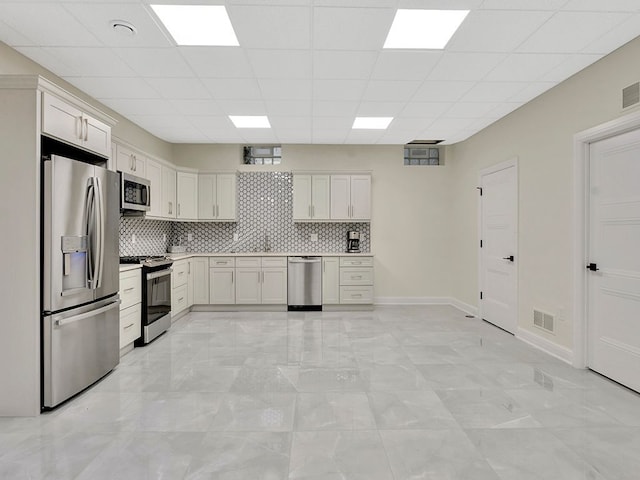 kitchen featuring a paneled ceiling, decorative backsplash, white cabinetry, and stainless steel appliances