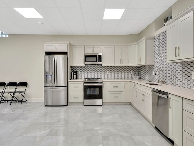 kitchen featuring tasteful backsplash, sink, a drop ceiling, and appliances with stainless steel finishes