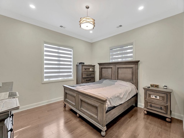 bedroom featuring hardwood / wood-style flooring, crown molding, and multiple windows