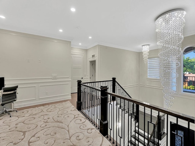 hallway with hardwood / wood-style flooring, crown molding, and an inviting chandelier