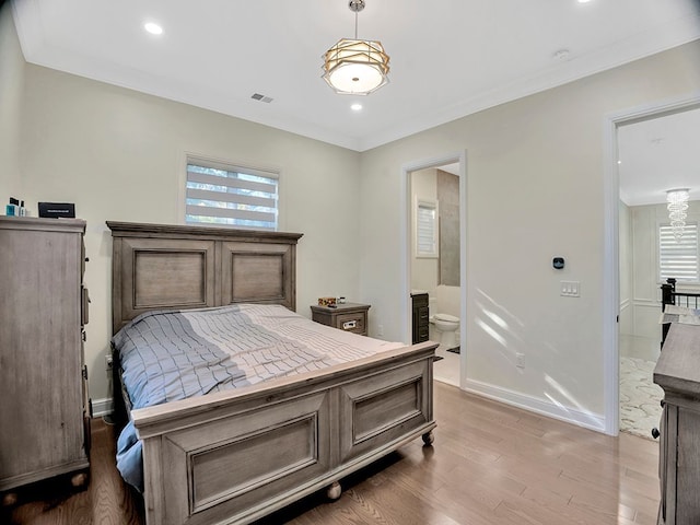 bedroom with connected bathroom, hardwood / wood-style floors, and ornamental molding