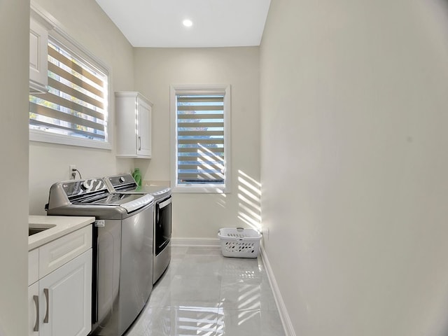 washroom featuring cabinets, washing machine and dryer, and a wealth of natural light