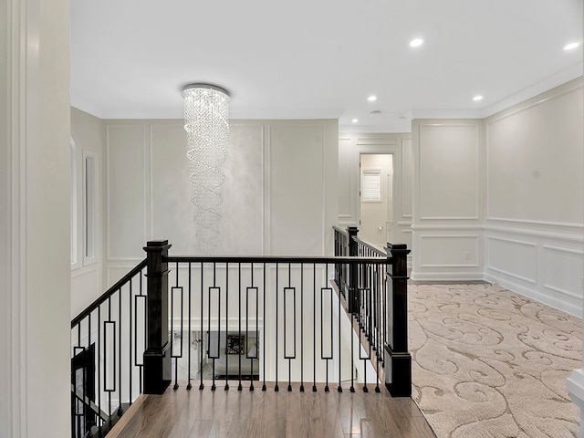 hallway featuring an inviting chandelier, ornamental molding, and light wood-type flooring