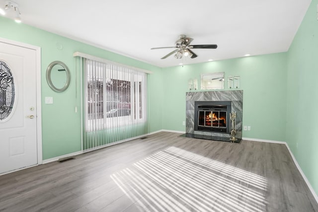 unfurnished living room with hardwood / wood-style flooring, ceiling fan, and a premium fireplace