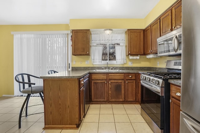 kitchen featuring light tile patterned floors, kitchen peninsula, sink, and appliances with stainless steel finishes