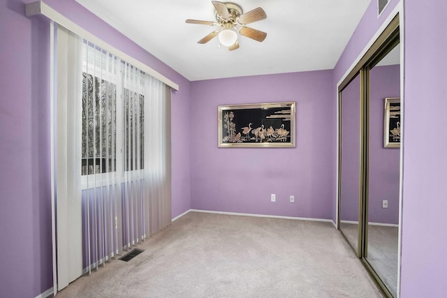 unfurnished bedroom featuring ceiling fan, light carpet, and a closet