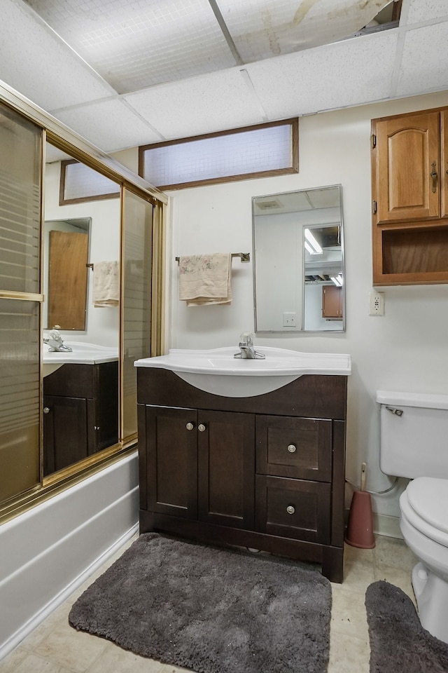 full bathroom with tile patterned flooring, vanity, bath / shower combo with glass door, and toilet