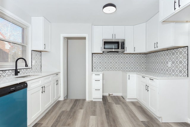 kitchen featuring backsplash, sink, light wood-type flooring, appliances with stainless steel finishes, and white cabinetry