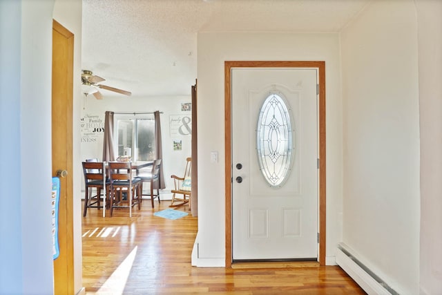 entryway with a baseboard radiator, light wood-type flooring, a textured ceiling, and a wealth of natural light