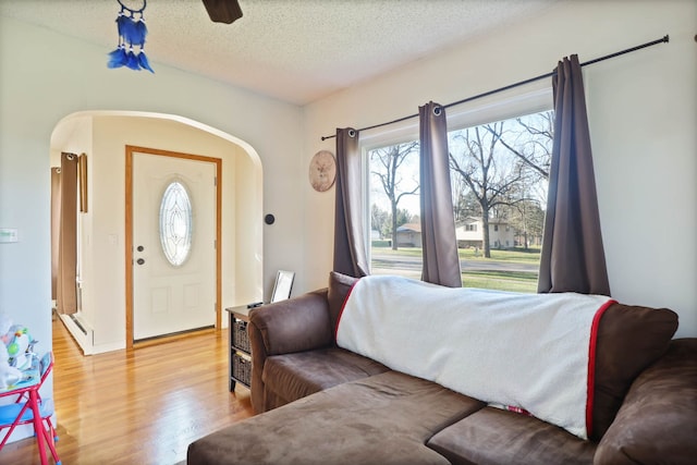 bedroom with ceiling fan, light hardwood / wood-style floors, and a textured ceiling