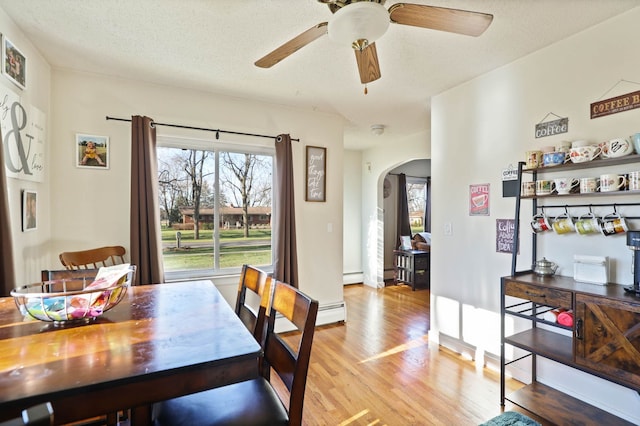 dining area featuring ceiling fan, a baseboard heating unit, light hardwood / wood-style flooring, and a textured ceiling