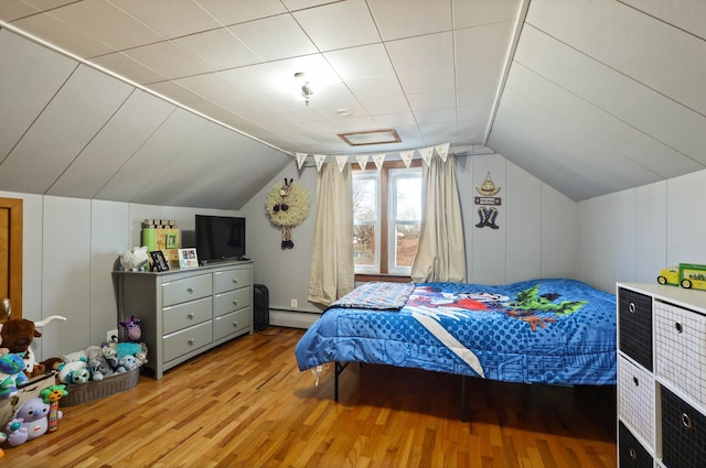 bedroom with a baseboard radiator, lofted ceiling, and light wood-type flooring